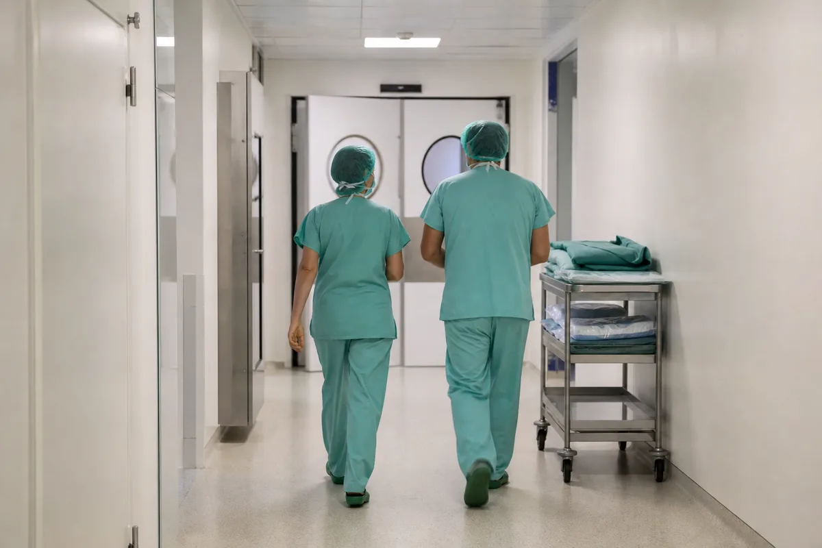 Couloir de bloc opératoire avec équipe soignante de dos en tenue chirurgicale
